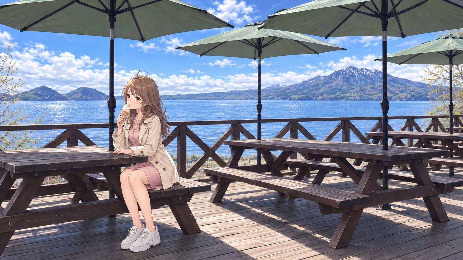 A woman in a cream-coloured coat, pale pink dress, tights and white trainers sits on a wooden bench on the restaurant terrace at Poropinai in spring. She brings a soft-serve cone to her mouth with one hand and rests the other on the table. Beyond the green parasol and wooden railing are the lake and mountains still covered in snow.