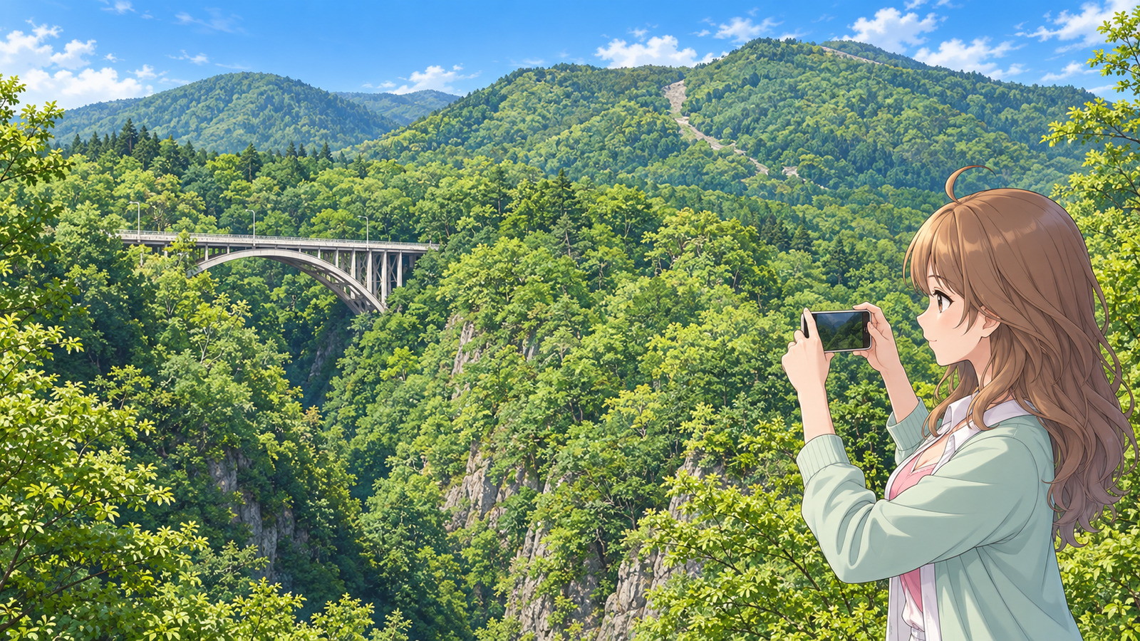 A woman with long brown hair in a white shirt and pink top with a mint cardigan layered over them, holding her smartphone horizontally in both hands, with Naruko Gorge in fresh spring foliage and Ōfukazawa Bridge in the upper left behind her